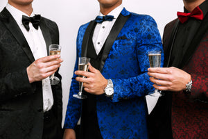 Three men in custom tailored black, blue, and red tuxedo suits